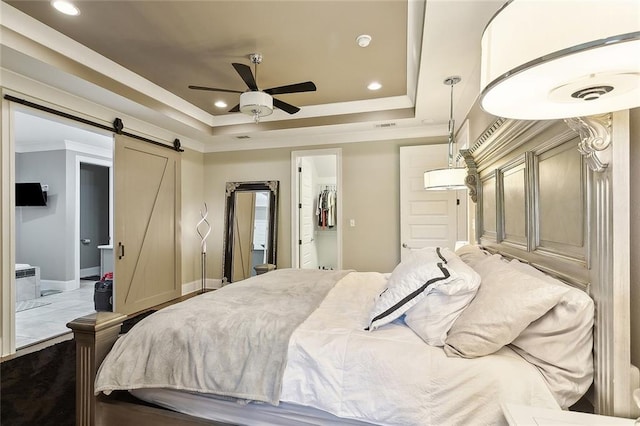 317 E Augusta Ln, Slidell, LA 70458 - bedroom featuring a tray ceiling, a barn door, crown molding, recessed lighting, and a walk in closet