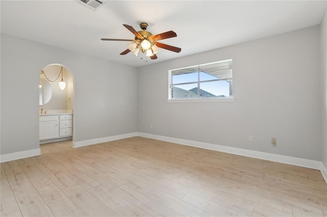 4901 Friar Tuck Dr, New Orleans, LA 70128 - empty room featuring a ceiling fan, light wood finished floors, baseboards, arched walkways, and a sink