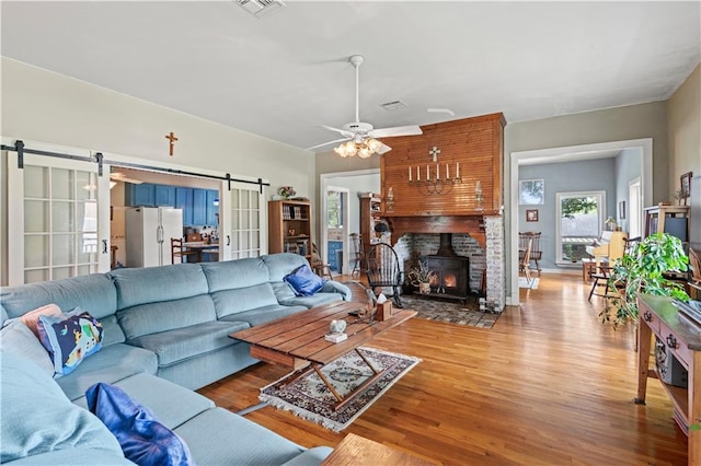 237 Villere Dr, Destrehan, LA 70047 - living room featuring a barn door, wood finished floors, a ceiling fan, and a wood stove