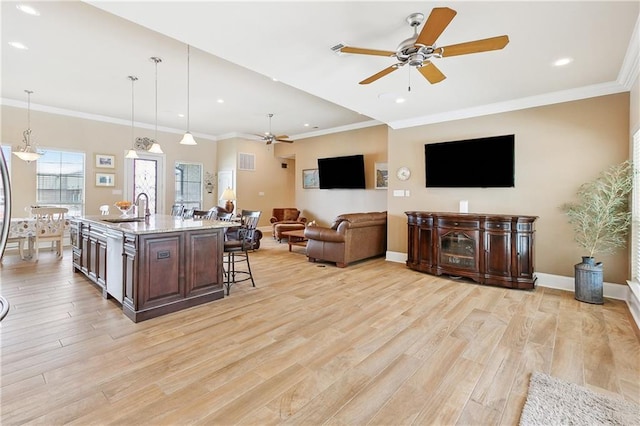 5001 Randolph St, Marrero, LA 70072 - kitchen with ceiling fan, a sink, a breakfast bar area, light wood-style flooring, and light stone countertops