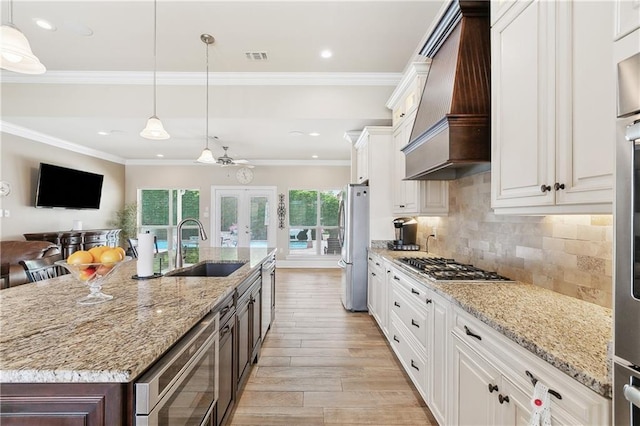 5001 Randolph St, Marrero, LA 70072 - kitchen with custom exhaust hood, appliances with stainless steel finishes, french doors, light wood finished floors, and a sink