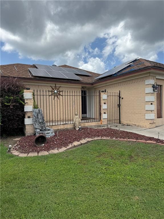 13801 Horizon Dr, New Orleans, LA 70129 - rear view of house featuring a yard, roof mounted solar panels, brick siding, and an attached garage