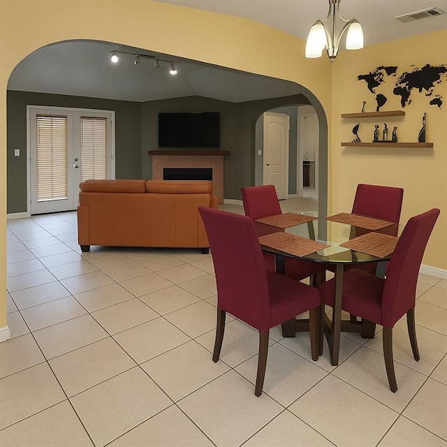 13801 Horizon Dr, New Orleans, LA 70129 - dining area featuring arched walkways, a fireplace, baseboards, light tile patterned floors, and rail lighting