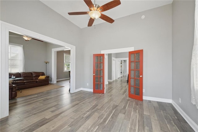 5530 Dauphine St, New Orleans, LA 70117 - spare room featuring french doors, wood finished floors, ceiling fan, a high ceiling, and baseboards