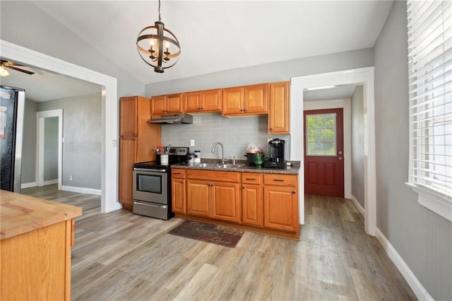 5530 Dauphine St, New Orleans, LA 70117 - kitchen with stainless steel electric stove, a sink, light wood-style flooring, under cabinet range hood, and a chandelier