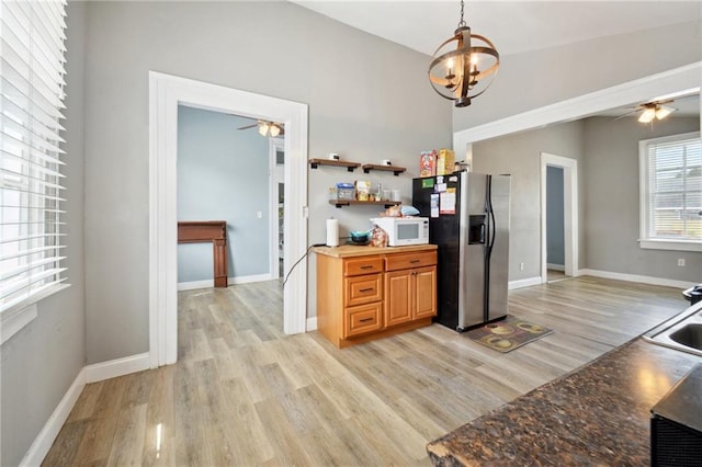 5530 Dauphine St, New Orleans, LA 70117 - kitchen with stainless steel fridge, white microwave, a ceiling fan, light wood-style floors, and baseboards