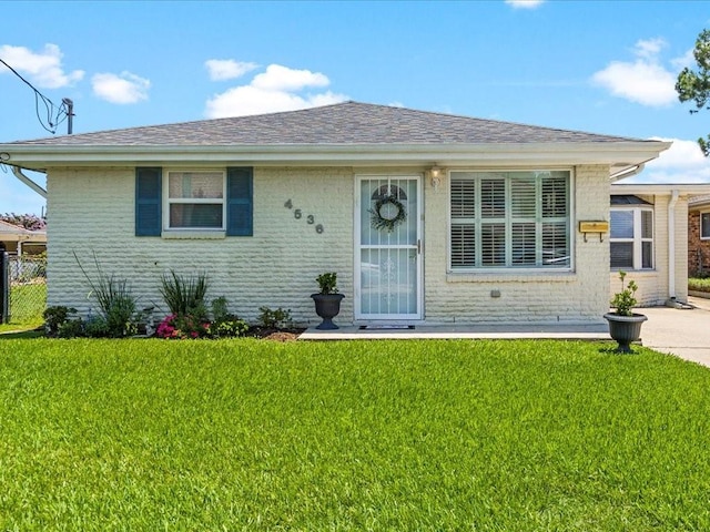 4536 Jasper St, Metairie, LA 70006 - view of front facade with a front yard, brick siding, and roof with shingles