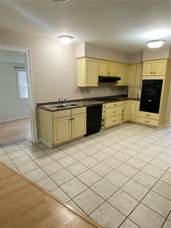 4536 Jasper St, Metairie, LA 70006 - kitchen with cream cabinets, black appliances, under cabinet range hood, a sink, and dark countertops