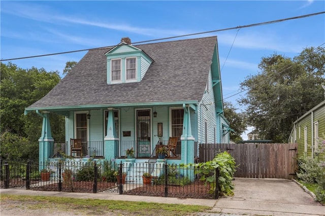 518 Pacific Ave, New Orleans, LA 70114 - view of front of home with covered porch, roof with shingles, a fenced front yard, and a chimney