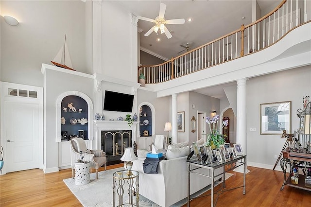 279 Debbie Dr, Slidell, LA 70458 - living area with a towering ceiling, a fireplace with raised hearth, ceiling fan, wood finished floors, and decorative columns