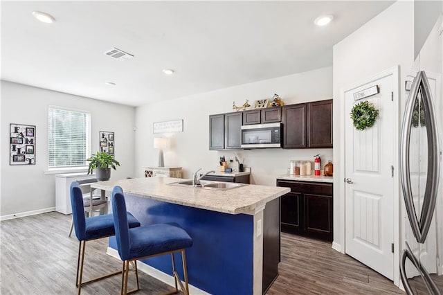 18181 Fox Hollow Loop, Hammond, LA 70401 - kitchen with appliances with stainless steel finishes, dark brown cabinetry, a sink, wood finished floors, and a kitchen island with sink
