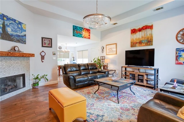 70046 9th St, Covington, LA 70433 - living room featuring a chandelier, wood finished floors, baseboards, a fireplace, and a raised ceiling