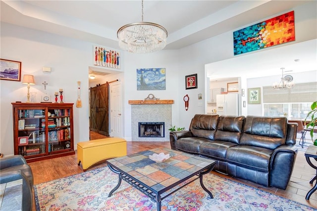 70046 9th St, Covington, LA 70433 - living room featuring a chandelier, a barn door, wood finished floors, and a tiled fireplace
