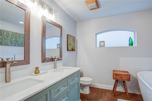 70046 9th St, Covington, LA 70433 - bathroom featuring a soaking tub, double vanity, wood finished floors, toilet, and baseboards