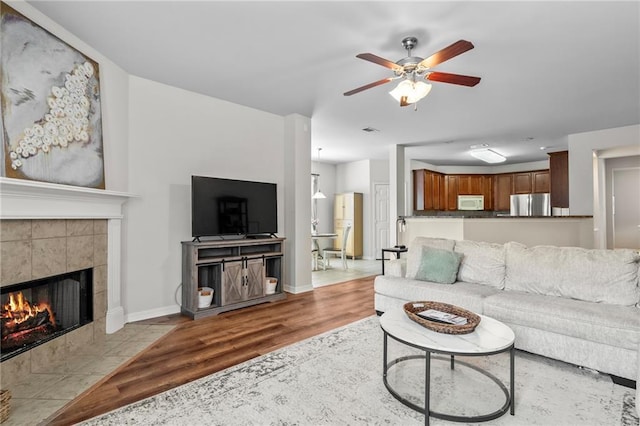 526 Moore Blvd, Covington, LA 70433 - living area featuring wood finished floors, a tiled fireplace, a ceiling fan, and baseboards