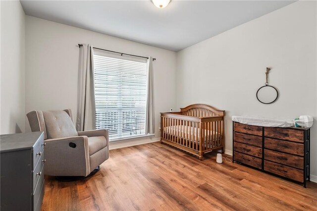 526 Moore Blvd, Covington, LA 70433 - bedroom featuring wood finished floors, baseboards, and a nursery area