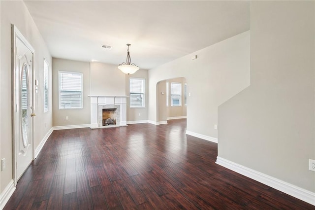 6409 Louis Xiv St, New Orleans, LA 70124 - unfurnished living room with arched walkways, dark wood-style floors, baseboards, and a fireplace