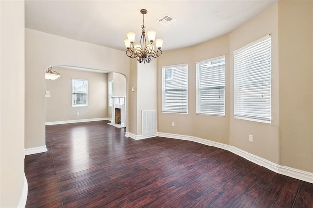 6409 Louis Xiv St, New Orleans, LA 70124 - empty room featuring wood finished floors, arched walkways, a chandelier, baseboards, and a fireplace with raised hearth
