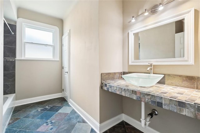 6409 Louis Xiv St, New Orleans, LA 70124 - bathroom featuring a sink, baseboards, stone finish flooring, and tub / shower combination