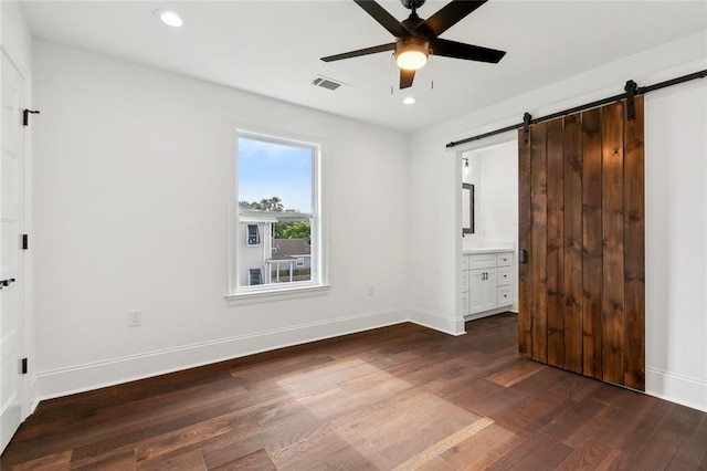 2824 Andover St, Jefferson, LA 70121 - unfurnished bedroom with a barn door, dark wood-type flooring, baseboards, recessed lighting, and connected bathroom