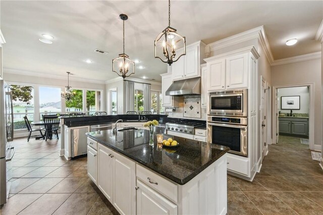 983 Lakeshore Blvd, Slidell, LA 70461 - kitchen with appliances with stainless steel finishes, under cabinet range hood, a chandelier, crown molding, and white cabinets