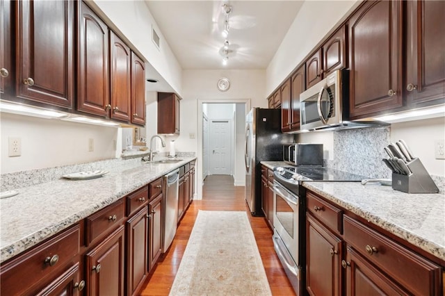 801 Rue Burgundy St Unit 113, Metairie, LA 70005 - kitchen featuring appliances with stainless steel finishes, a sink, light wood-style floors, light stone counters, and decorative backsplash