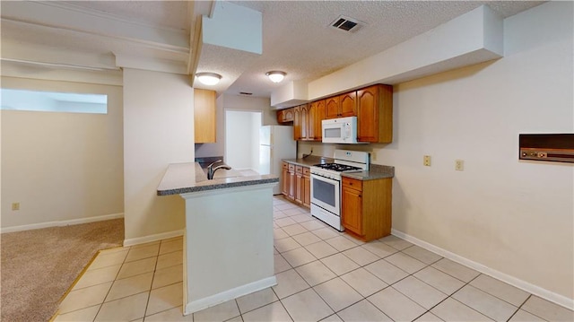 4813 Lake Como Ave, Metairie, LA 70006 - kitchen featuring white appliances, a textured ceiling, a peninsula, brown cabinets, and light tile patterned flooring