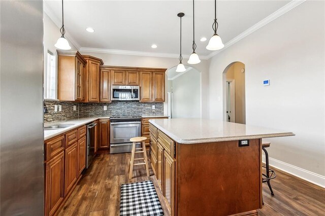 4850B Jean Lafitte Blvd, Jean Lafitte, LA 70067 - kitchen featuring appliances with stainless steel finishes, arched walkways, a breakfast bar, brown cabinets, and a center island
