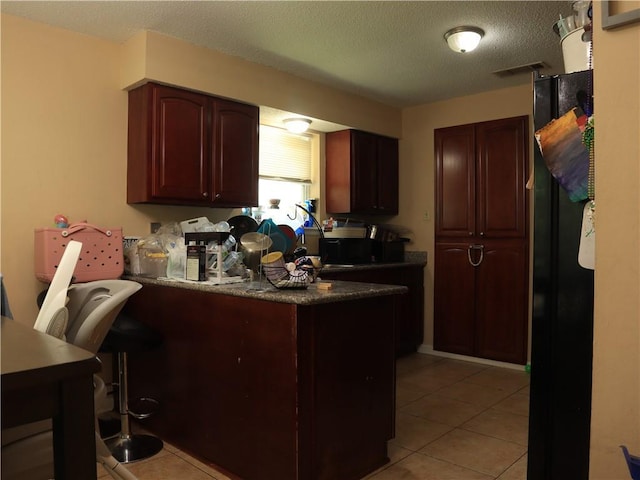 1604 Saint Christopher St, Slidell, LA 70460 - kitchen with a peninsula, light tile patterned floors, dark countertops, a textured ceiling, and a kitchen breakfast bar