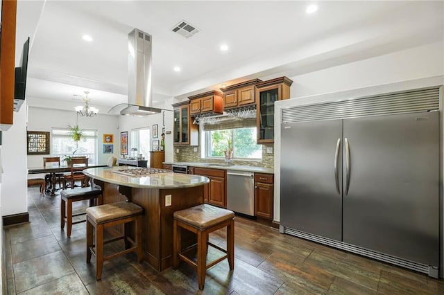 439 S Clark St, New Orleans, LA 70119 - kitchen with stainless steel appliances, island exhaust hood, brown cabinetry, a kitchen island, and plenty of natural light