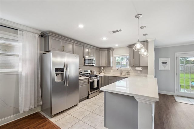 4709 Kawanee Ave, Metairie, LA 70006 - kitchen featuring stainless steel appliances, gray cabinets, a peninsula, light countertops, and healthy amount of natural light