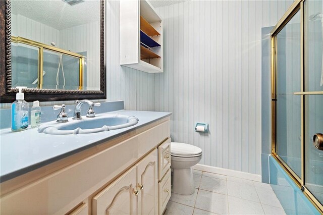 1816 Giuffrias Ave, Metairie, LA 70001 - full bathroom with vanity, baseboards, a textured ceiling, toilet, and bath / shower combo with glass door