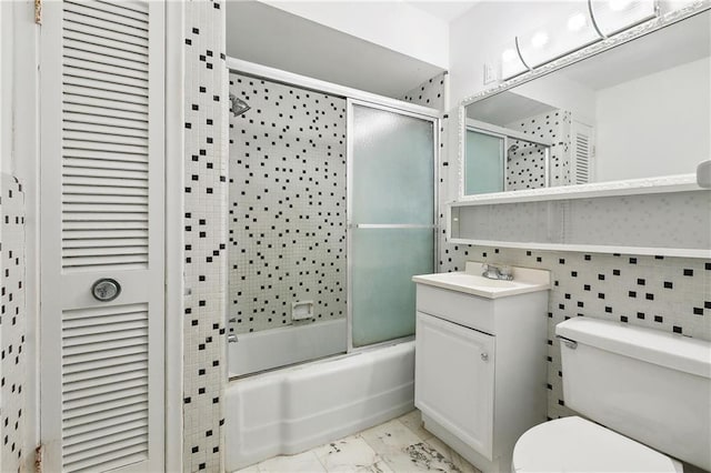 1501 Poinsettia Dr, Metairie, LA 70005 - bathroom featuring bath / shower combo with glass door, vanity, toilet, marble finish floors, and tile walls
