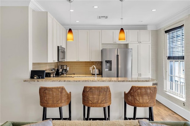 220 Decatur St Unit 302, New Orleans, LA 70130 - kitchen with stainless steel appliances, a breakfast bar area, white cabinets, ornamental molding, and tasteful backsplash