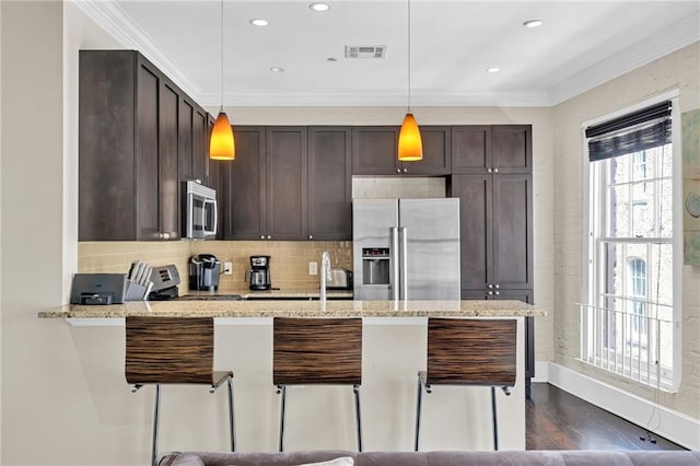 220 Decatur St Unit 304, New Orleans, LA 70130 - kitchen featuring stainless steel appliances, dark brown cabinets, ornamental molding, a breakfast bar, and pendant lighting
