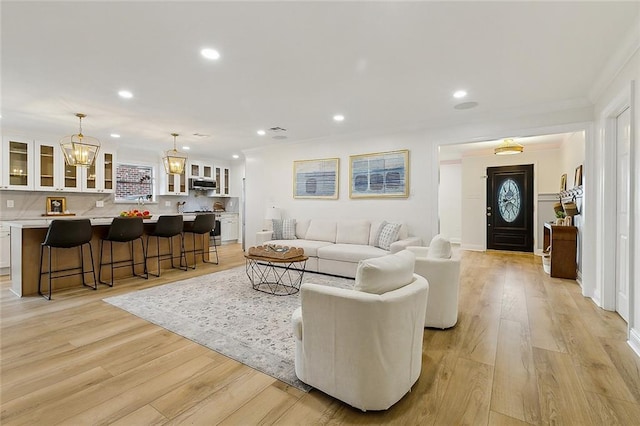 4721 Chastant St, Metairie, LA 70006 - living room with crown molding, light wood-style flooring, recessed lighting, and a chandelier