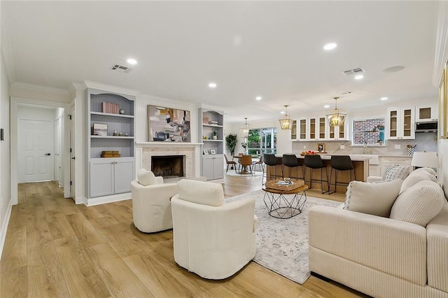 4721 Chastant St, Metairie, LA 70006 - living room featuring crown molding, recessed lighting, light wood finished floors, a fireplace, and a chandelier