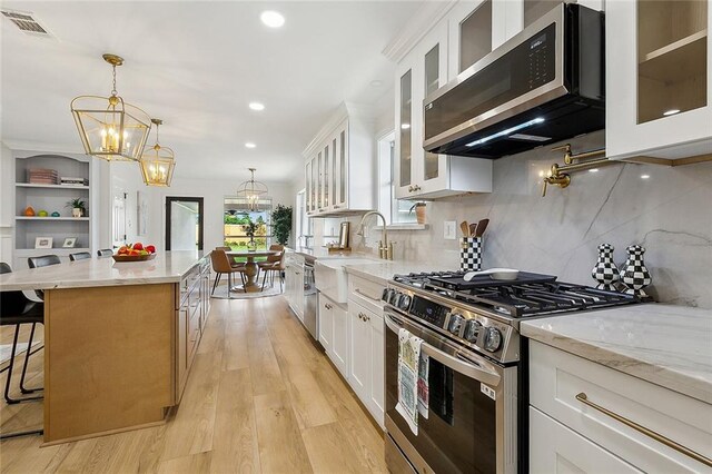 4721 Chastant St, Metairie, LA 70006 - kitchen with stainless steel appliances, a chandelier, a sink, a center island, and light stone countertops