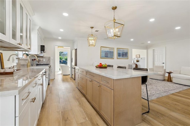 4721 Chastant St, Metairie, LA 70006 - kitchen featuring freestanding refrigerator, a breakfast bar area, light wood-style floors, recessed lighting, and light stone counters
