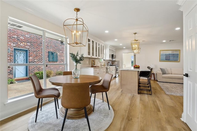4721 Chastant St, Metairie, LA 70006 - dining room featuring a chandelier, light wood-style flooring, healthy amount of natural light, recessed lighting, and crown molding