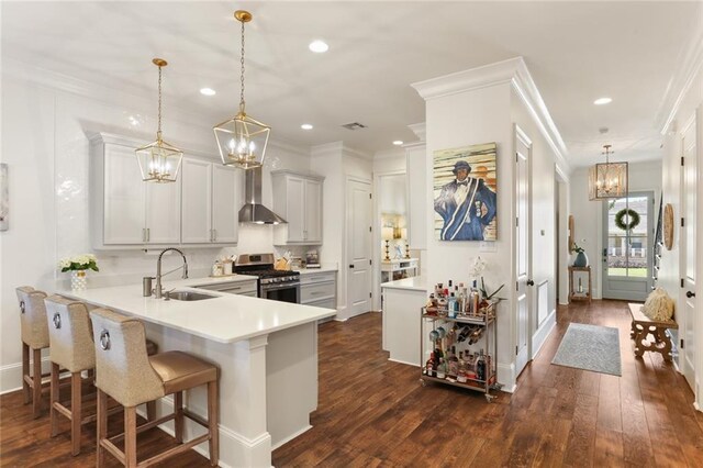 247 26th St, New Orleans, LA 70124 - kitchen featuring gas stove, a chandelier, a sink, wall chimney range hood, and dark wood-style floors