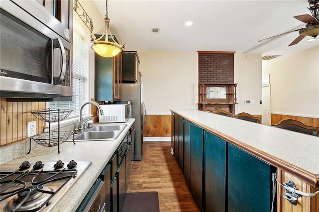 1509 N Derbigny St, New Orleans, LA 70116 - kitchen featuring appliances with stainless steel finishes, a ceiling fan, wainscoting, dark wood-style flooring, and a sink