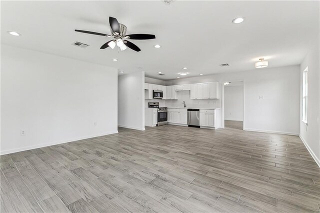 7504 Birch St, Violet, LA 70092 - unfurnished living room with light wood-style floors, baseboards, recessed lighting, a ceiling fan, and a sink