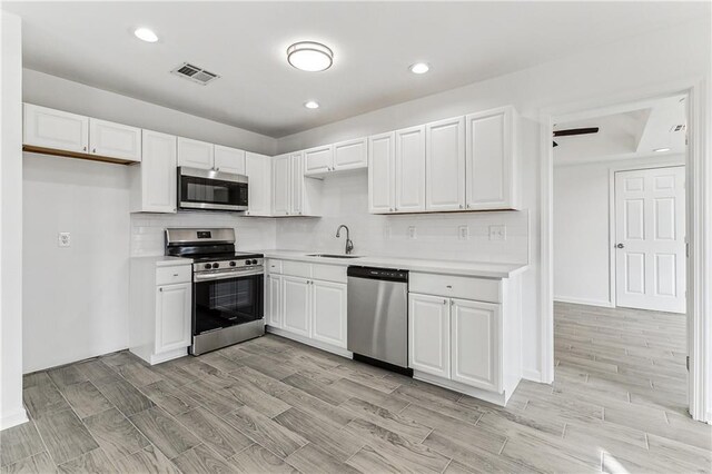 7504 Birch St, Violet, LA 70092 - kitchen featuring appliances with stainless steel finishes, a sink, light countertops, white cabinets, and backsplash
