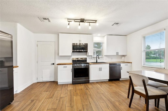 67 Cochrane Dr, Chalmette, LA 70043 - kitchen with appliances with stainless steel finishes, a sink, a textured ceiling, light wood-style flooring, and plenty of natural light