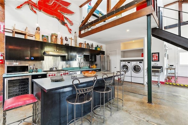 3300 Dumaine St, New Orleans, LA 70119 - kitchen with separate washer and dryer, appliances with stainless steel finishes, wine cooler, concrete floors, and a breakfast bar