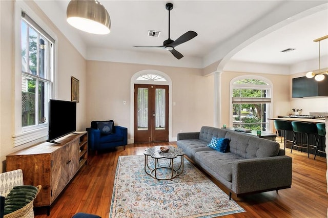 1500 Camp St, New Orleans, LA 70130 - living room featuring arched walkways, a ceiling fan, wood finished floors, decorative columns, and french doors