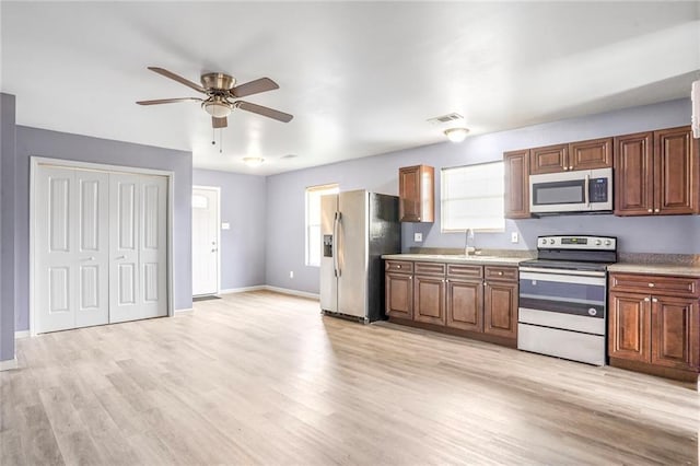 1319 Granada Dr, New Orleans, LA 70122 - kitchen featuring appliances with stainless steel finishes, ceiling fan, light wood finished floors, a sink, and light countertops