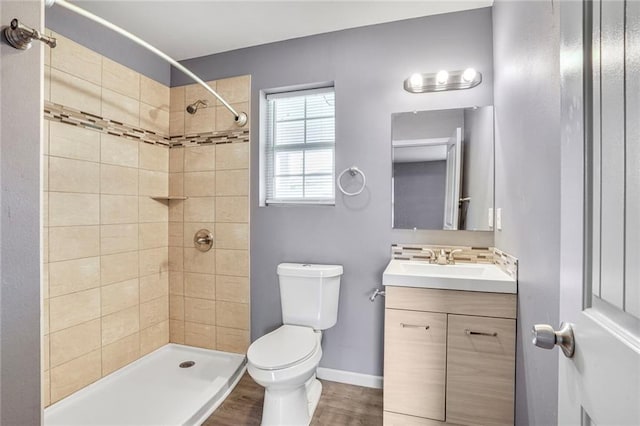 1319 Granada Dr, New Orleans, LA 70122 - bathroom with toilet, vanity, tiled shower, wood finished floors, and baseboards