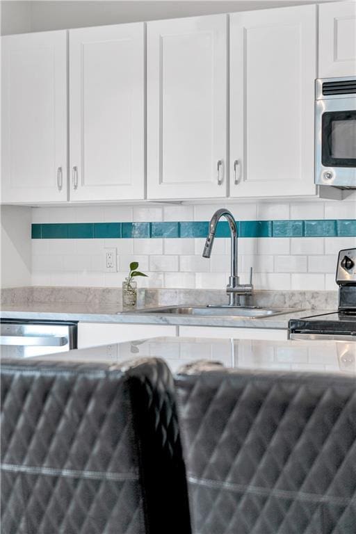 2833 St Charles Ave Unit 16, New Orleans, LA 70115 - kitchen featuring a sink, white cabinets, electric range, decorative backsplash, and light stone counters